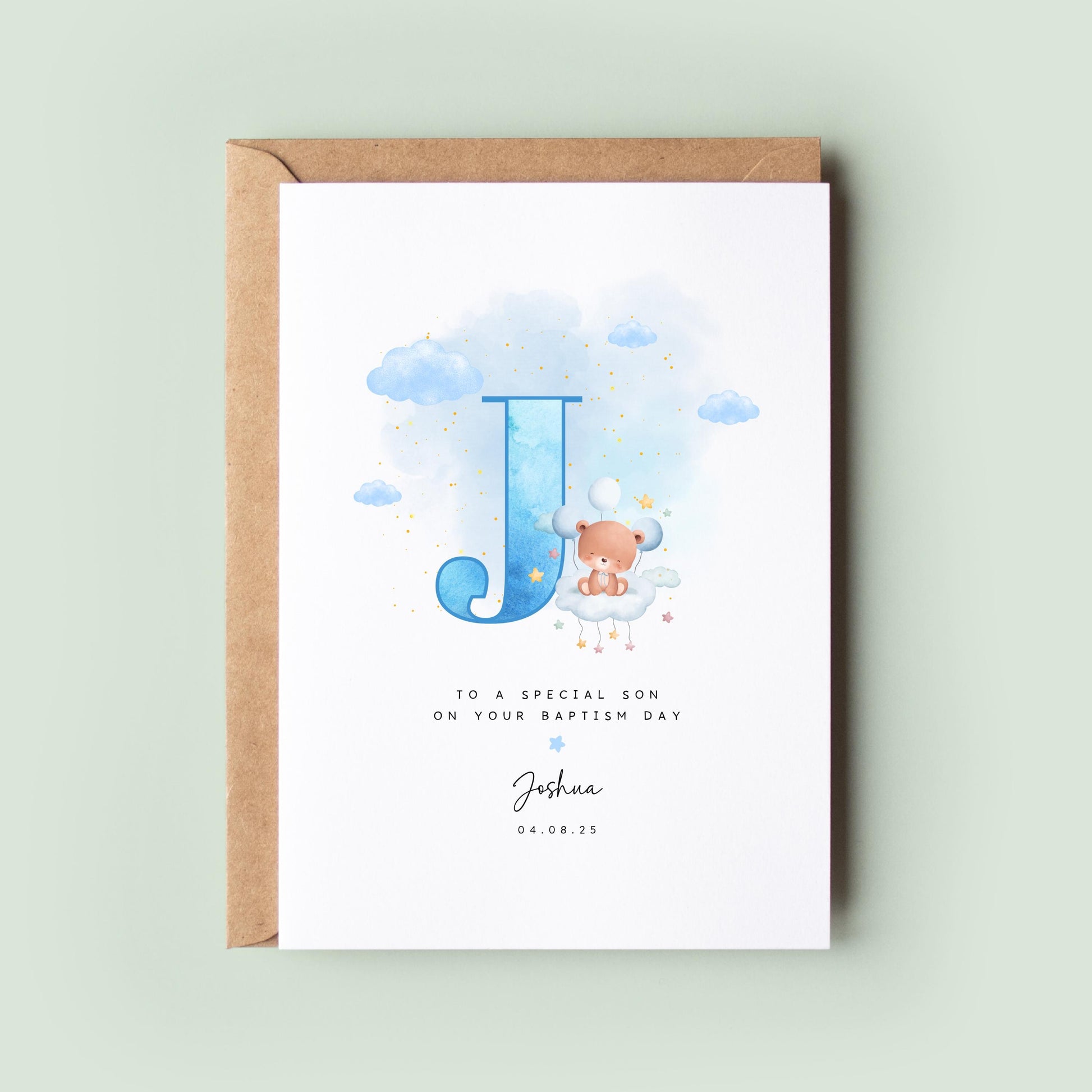 Personalised baptism card featuring a large blue letter “J” with a teddy bear sitting on a cloud. The text reads “To a special son on your baptism day,” followed by the name “Joshua” and date. Comes with a recycled kraft envelope.