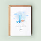 Personalised christening card featuring a large blue letter “J” with a teddy bear sitting on a cloud. The text reads “To a special grandson on your christening day,” followed by the name “Joshua” and date. Comes with a recycled kraft envelope.