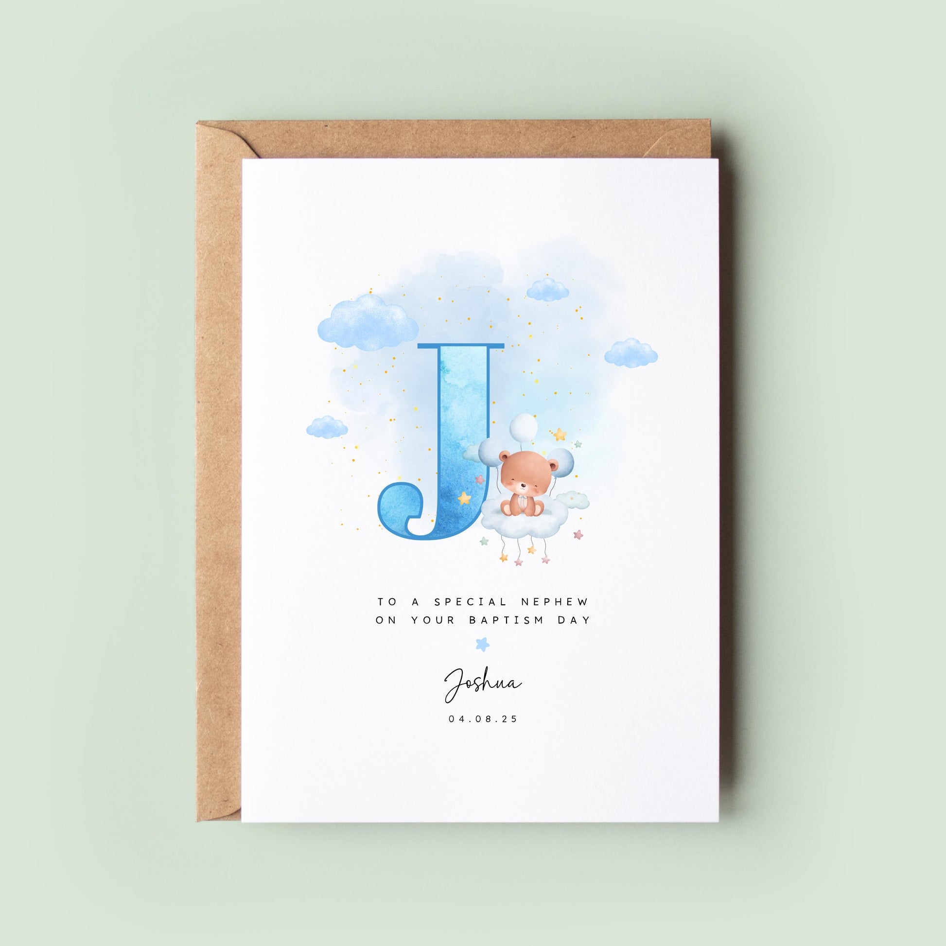 Personalised baptism card featuring a large blue letter “J” with a teddy bear sitting on a cloud. The text reads “To a special nephew on your baptism day,” followed by the name “Joshua” and date. Comes with a recycled kraft envelope.