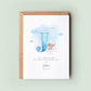 Personalised christening card featuring a large blue letter “J” with a teddy bear sitting on a cloud. The text reads “To a special boy on your christening day,” followed by the name “Joshua” and date. Comes with a recycled kraft envelope.