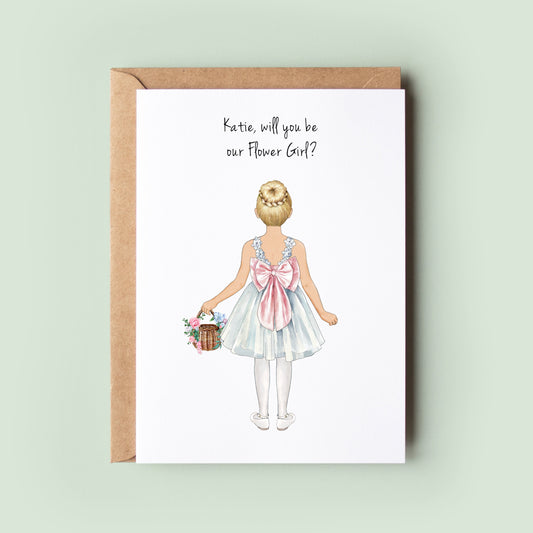 A close-up of a personalised Will You Be My Flower Girl, Will You Be My Junior Bridesmaid card featuring custom illustrations for the flower girl&#39;s dress, skin tone, and hairstyle.
